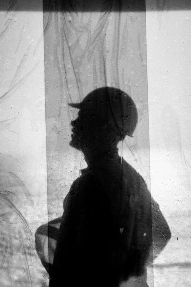 A dramatic black and white silhouette of a person wearing a cap, shot through a textured curtain for Usher Group.