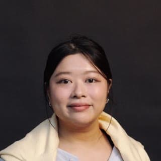 A studio headshot shows a young woman with dark hair wearing a cream cardigan against a dark background.