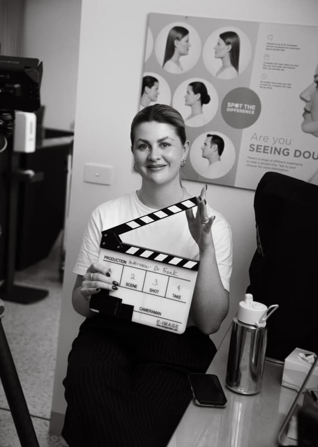 Producer holding a film slate before a shoot day, with the production fields filled in for an interview setup.