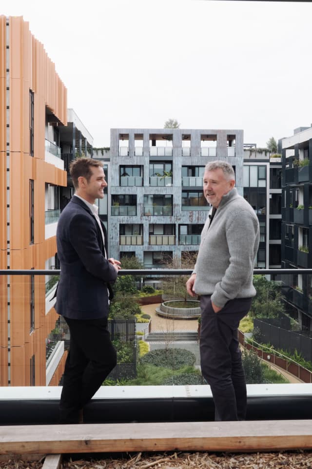 Two people talking on a balcony overlooking the internal courtyard at East Brunswick Village