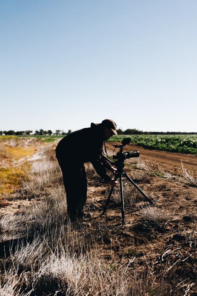For Providore Global, a silhouetted videographer films rows of crops on a tripod-mounted camera at sunset.