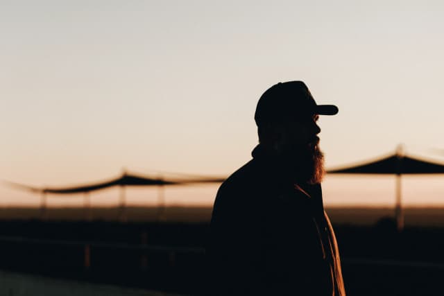 A silhouetted man in a cap watches the sunset near shade structures on a Providore Global farm in Garah.