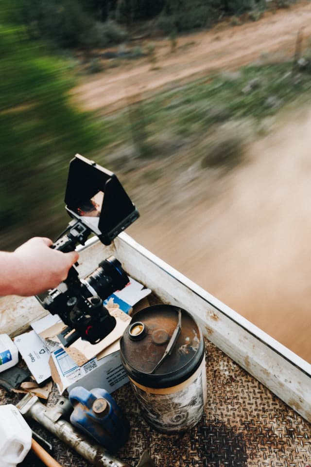 A camera mounted on a ute tray captures a blurred dirt road while driving on a Providore Global shoot.