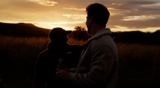 Two silhouetted men stand in golden light at sunset during a South African shoot.