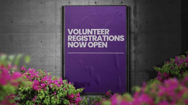 A purple poster reading volunteer registrations now open hangs on a concrete wall framed by pink bougainvillea.