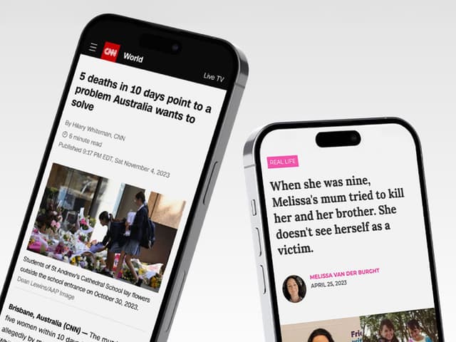 Two smartphones stand side by side displaying CNN news articles about real life stories against a plain grey backdrop.