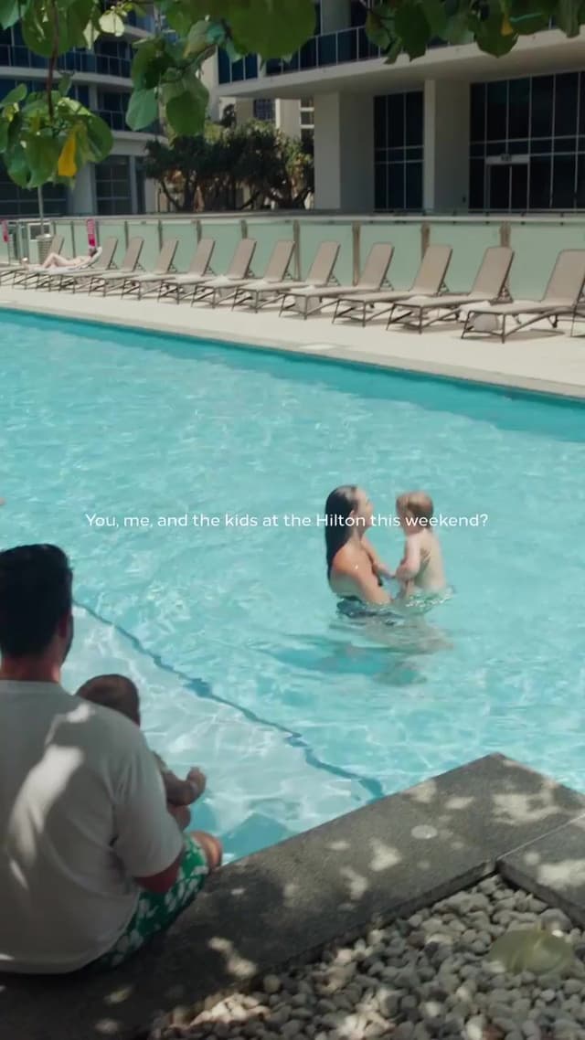 A family video still at a Hilton Surfers Paradise pool asks about booking a weekend stay together.
