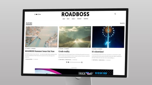 A desktop monitor displays the ROADBOSS website homepage featuring three magazine style story cards.