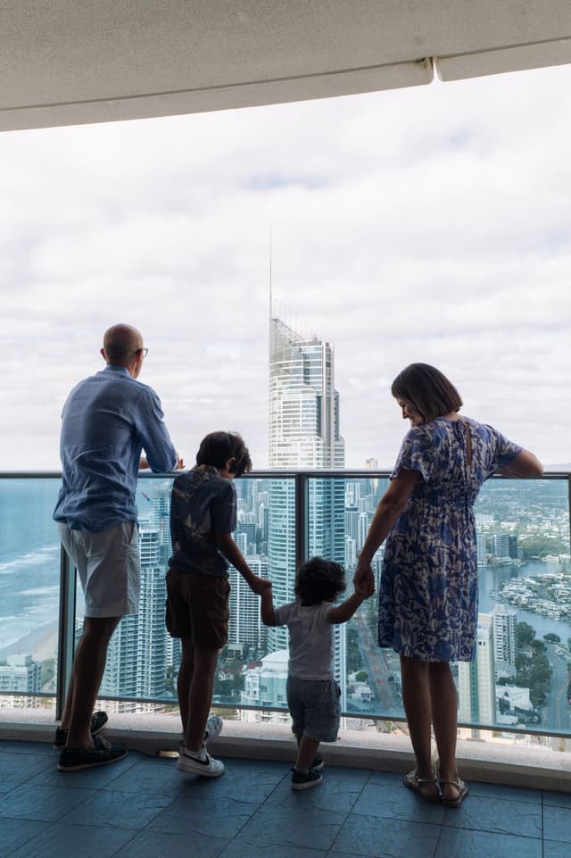 A family on a Hilton Surfers Paradise balcony looking over the Gold Coast skyline