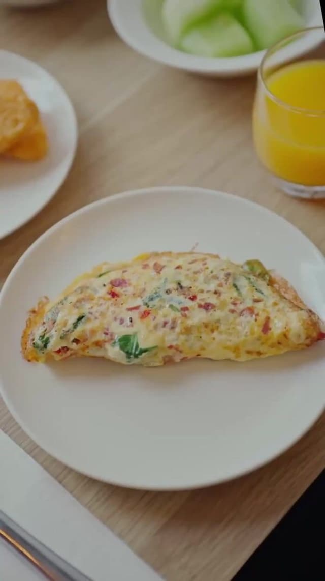 A Hilton Surfers Paradise room service breakfast of omelette, toast and orange juice on a wooden table.