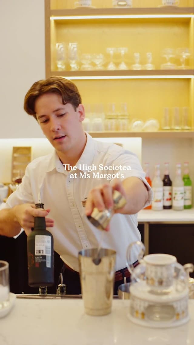 A bartender at Ms Margot's, inside Hilton Surfers Paradise, pours 'The High Societea' cocktail behind a shaker.
