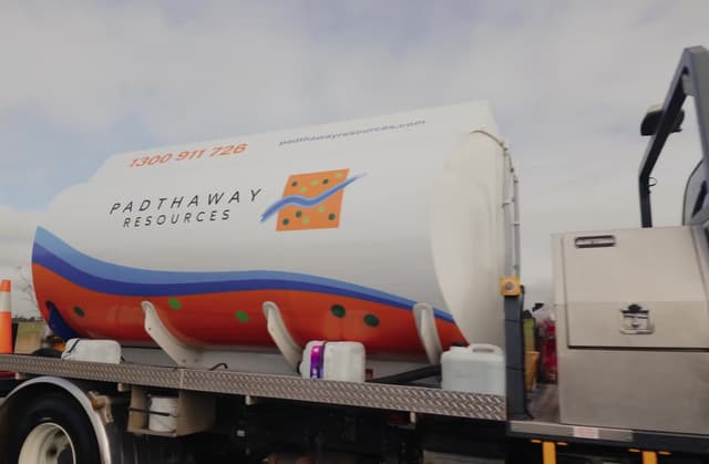 A branded water tanker truck for Padthaway Resources, painted white, orange and blue, parked on a flatbed trailer.