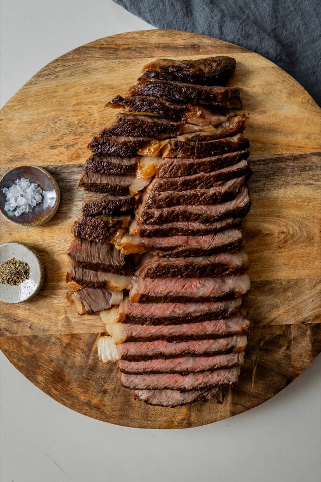 For Providore Global, a sliced medium-rare steak fans out on a round wooden board beside salt and pepper.
