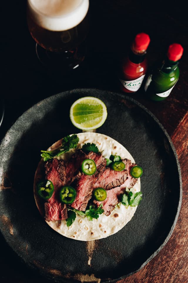 An overhead shot of a sliced steak taco topped with jalapenos and coriander, a Providore Global dish.
