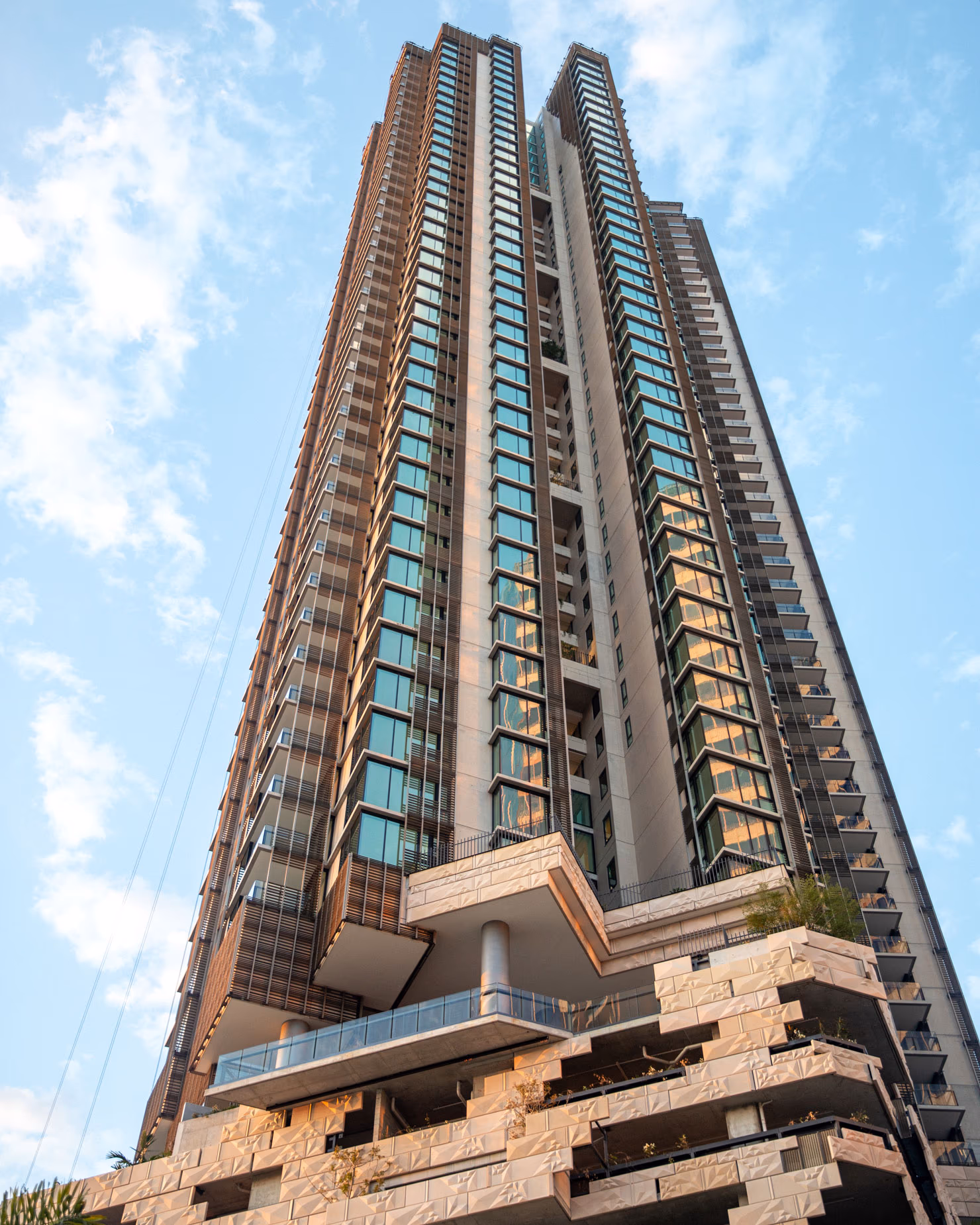 A high rise apartment tower for Usher Group rises against a blue sky, viewed from street level looking up.