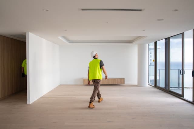 A hi-vis clad site supervisor inspects an empty high rise apartment with ocean views at an Usher Group project.