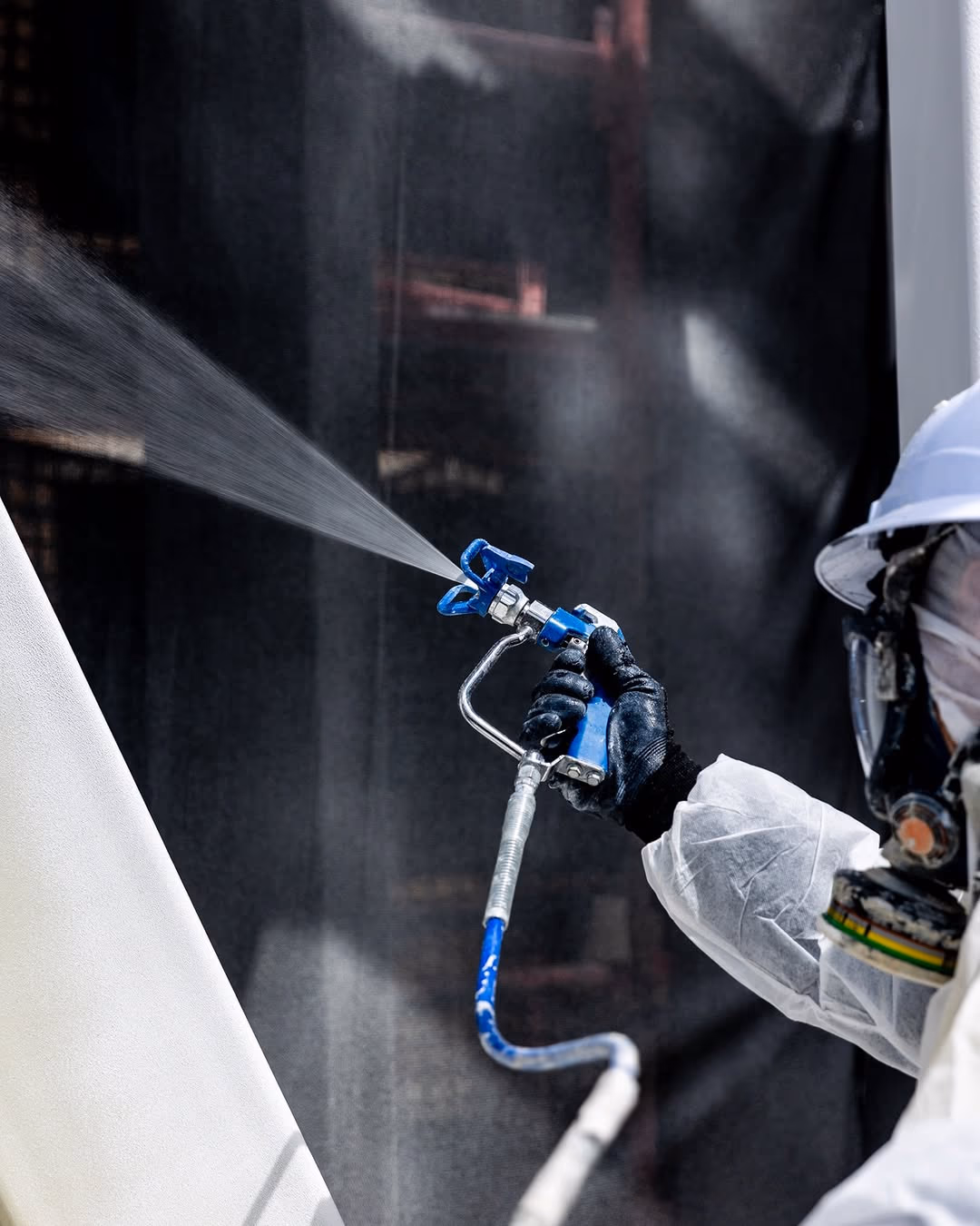 A worker in full protective gear spray-paints a surface on a Usher Group job site.