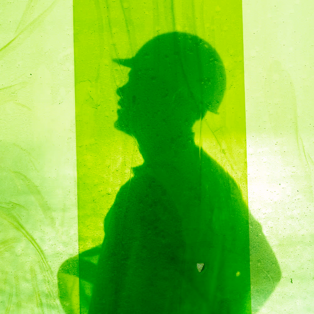 The silhouette of an Usher Group worker in a hard hat cast onto bright green protective sheeting.