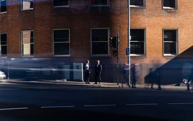 Two men in suits stand on a city street corner near Bent Street, with blurred pedestrians passing by, for Vantage Asset Management.