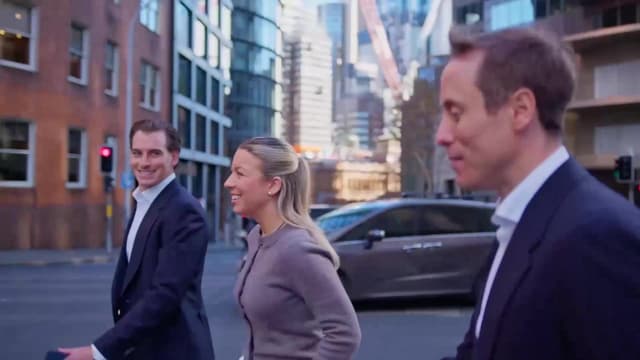 Three Vantage Asset Management colleagues in suits walk across a city street with high rise buildings behind them.