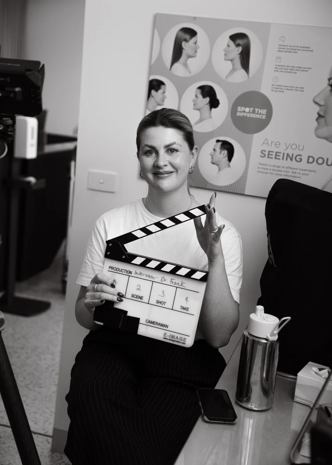 Producer holding a film slate before a shoot day, with the production fields filled in for an interview setup.