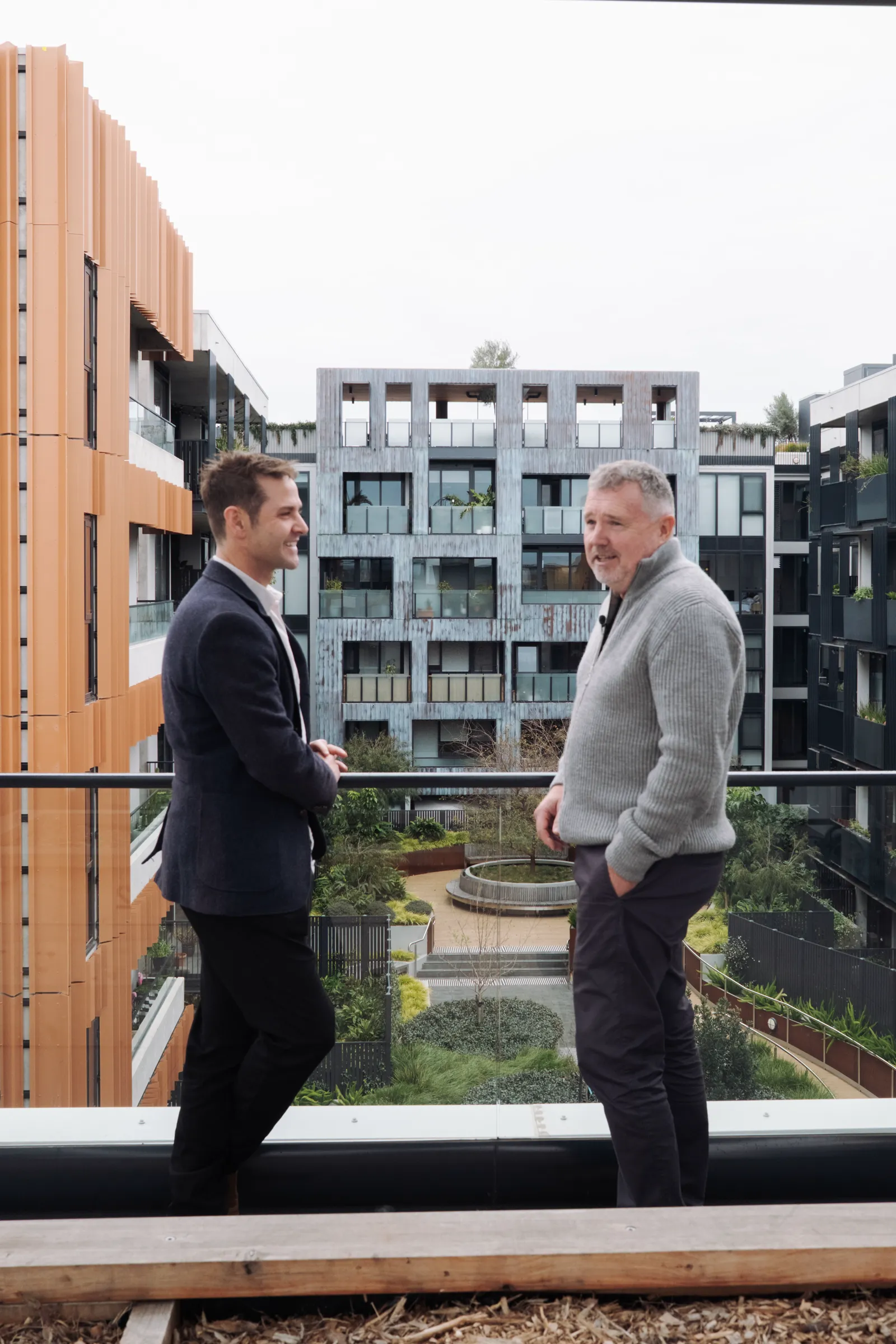 Two people talking on a balcony overlooking the internal courtyard at East Brunswick Village