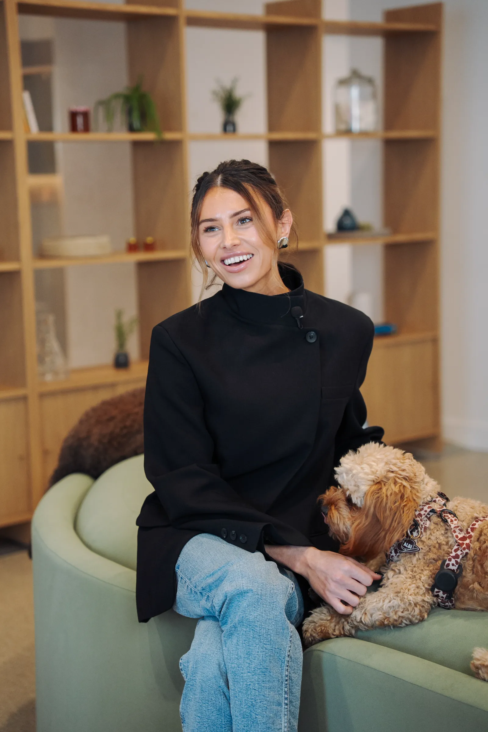 A person sitting on a sofa with a dog in a communal lounge at East Brunswick Village