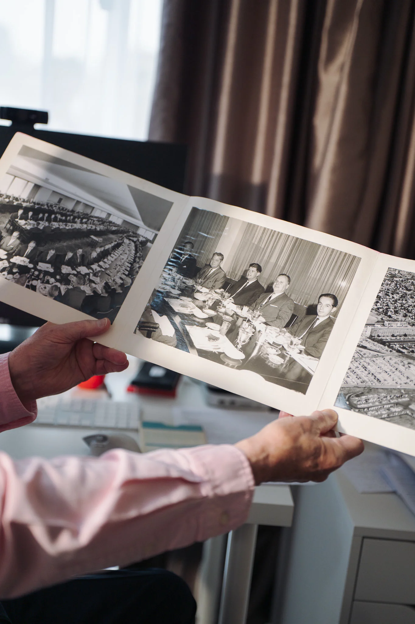 Tim holding up an old photo album of early computer rooms from his years in IT