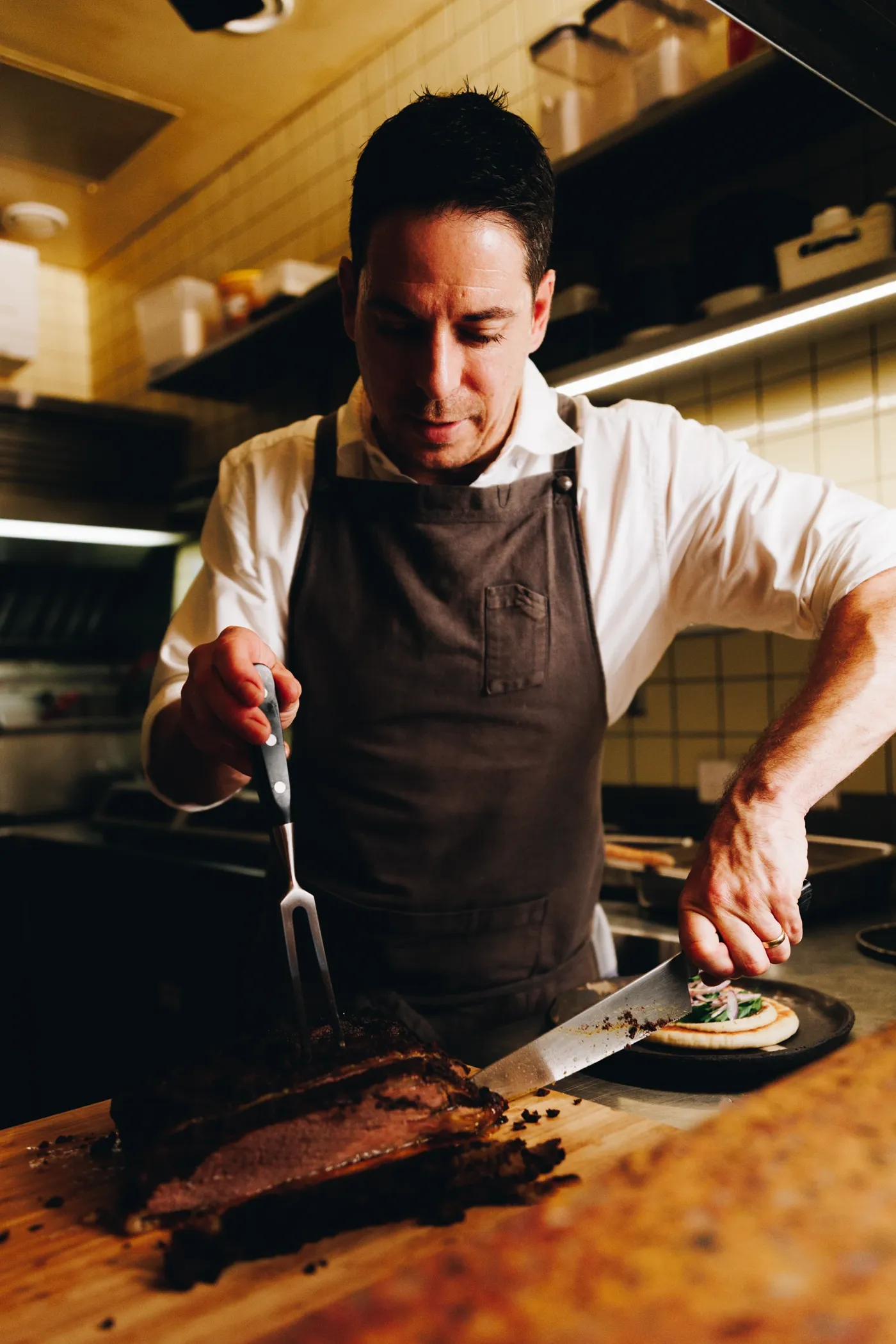 Chef Ian Oakes slicing and plating beef on the pass