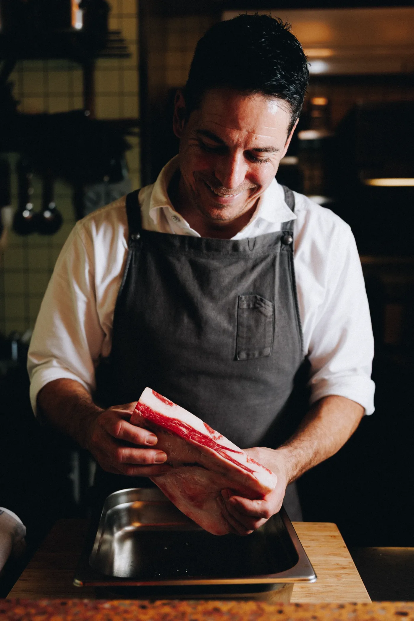 Chef Ian Oakes holding a beef rib over a tray in the kitchen at Mullumbimby