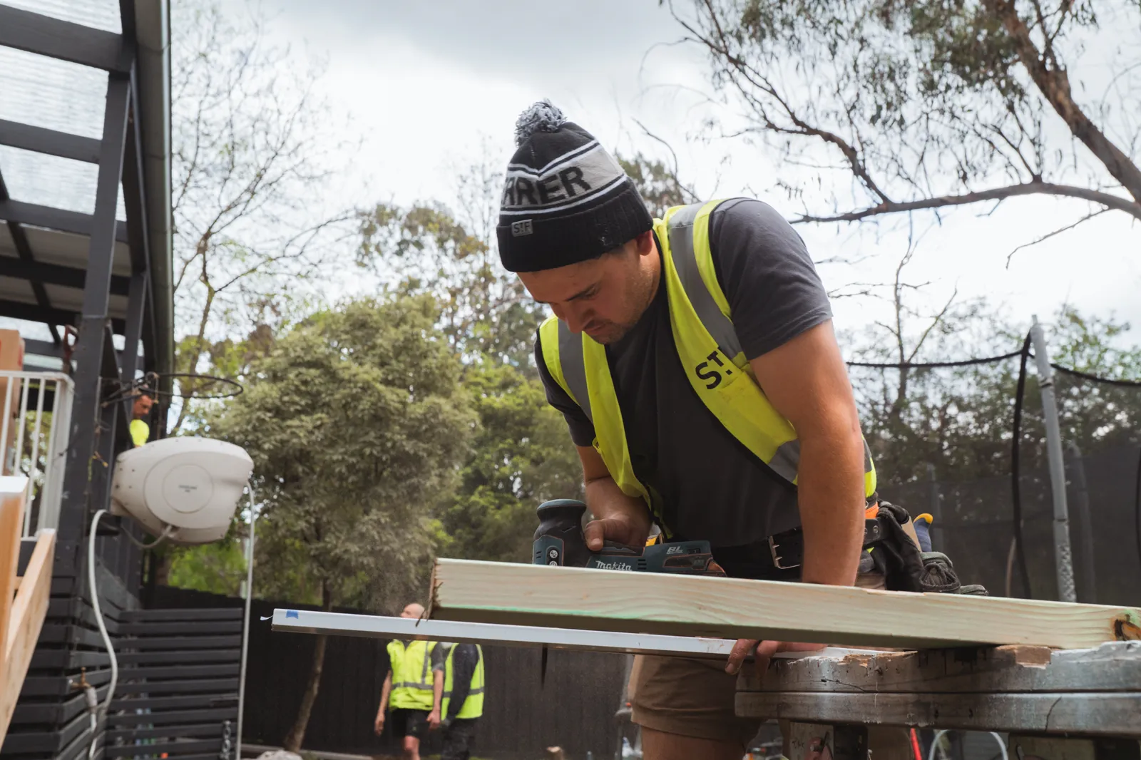 Trades and volunteers building the new deck at the back of the house on build day