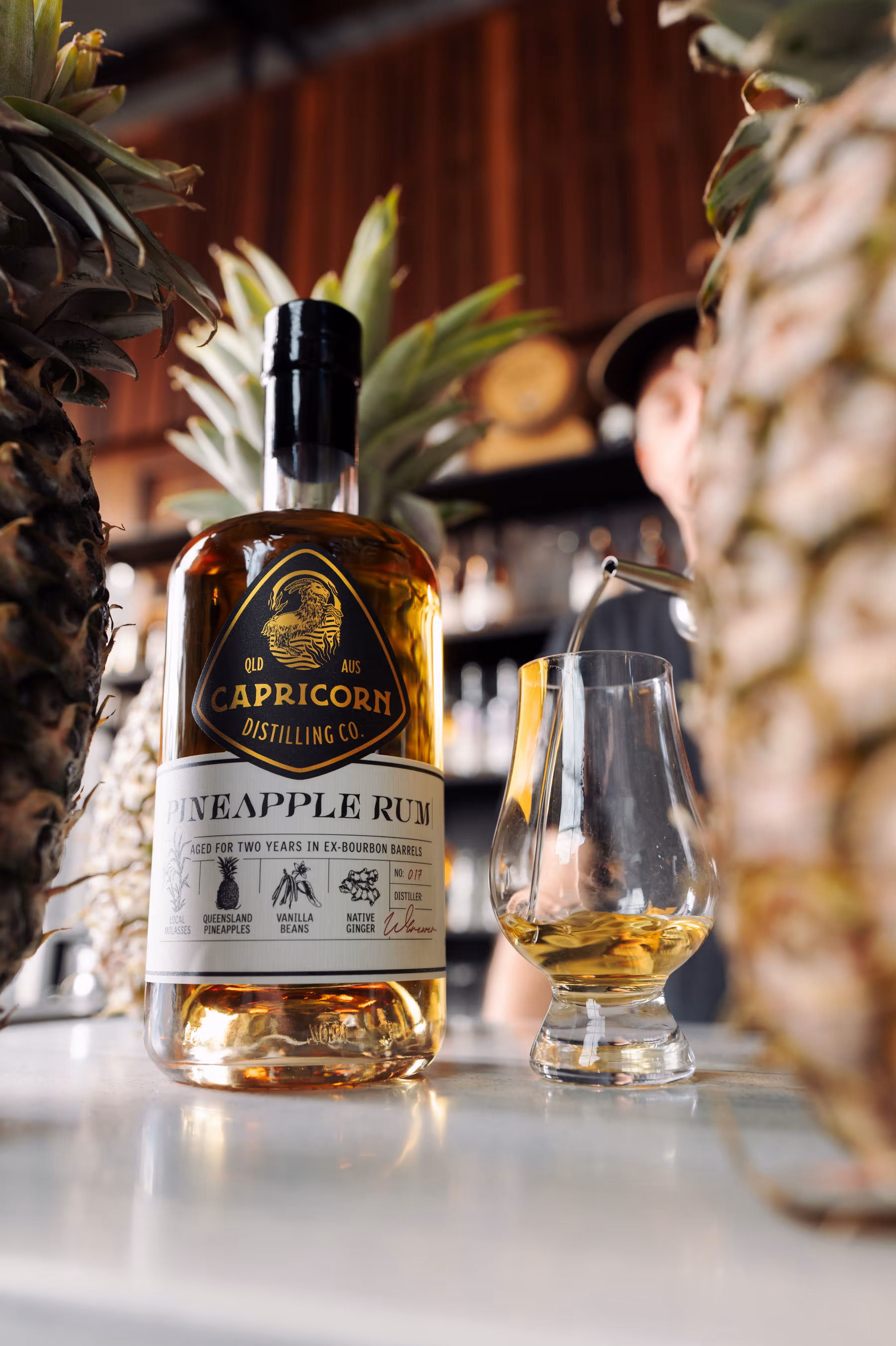 Capricorn Pineapple Rum poured beside fresh pineapple on the bar