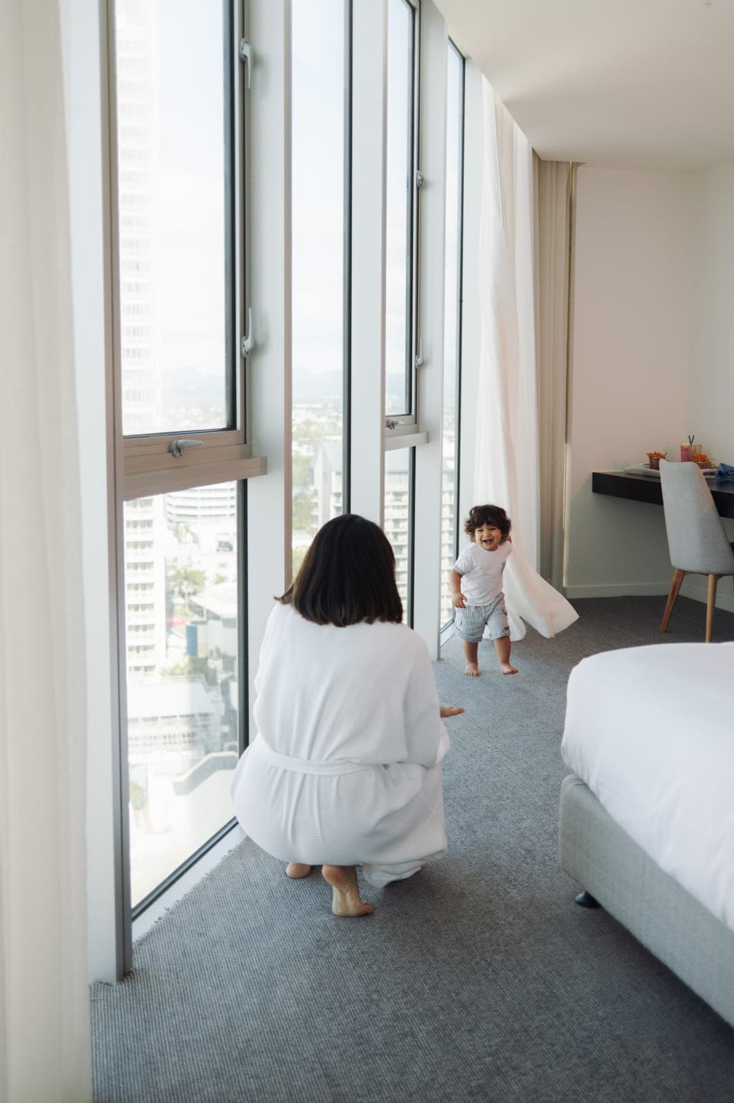 A guest and toddler at the floor-to-ceiling window of a Hilton Surfers Paradise room