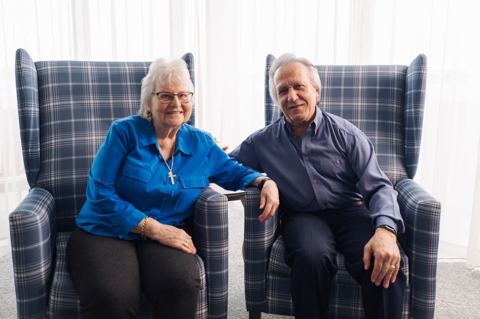 Savas and Georgia sitting together in armchairs by the window at John Hood Terrace