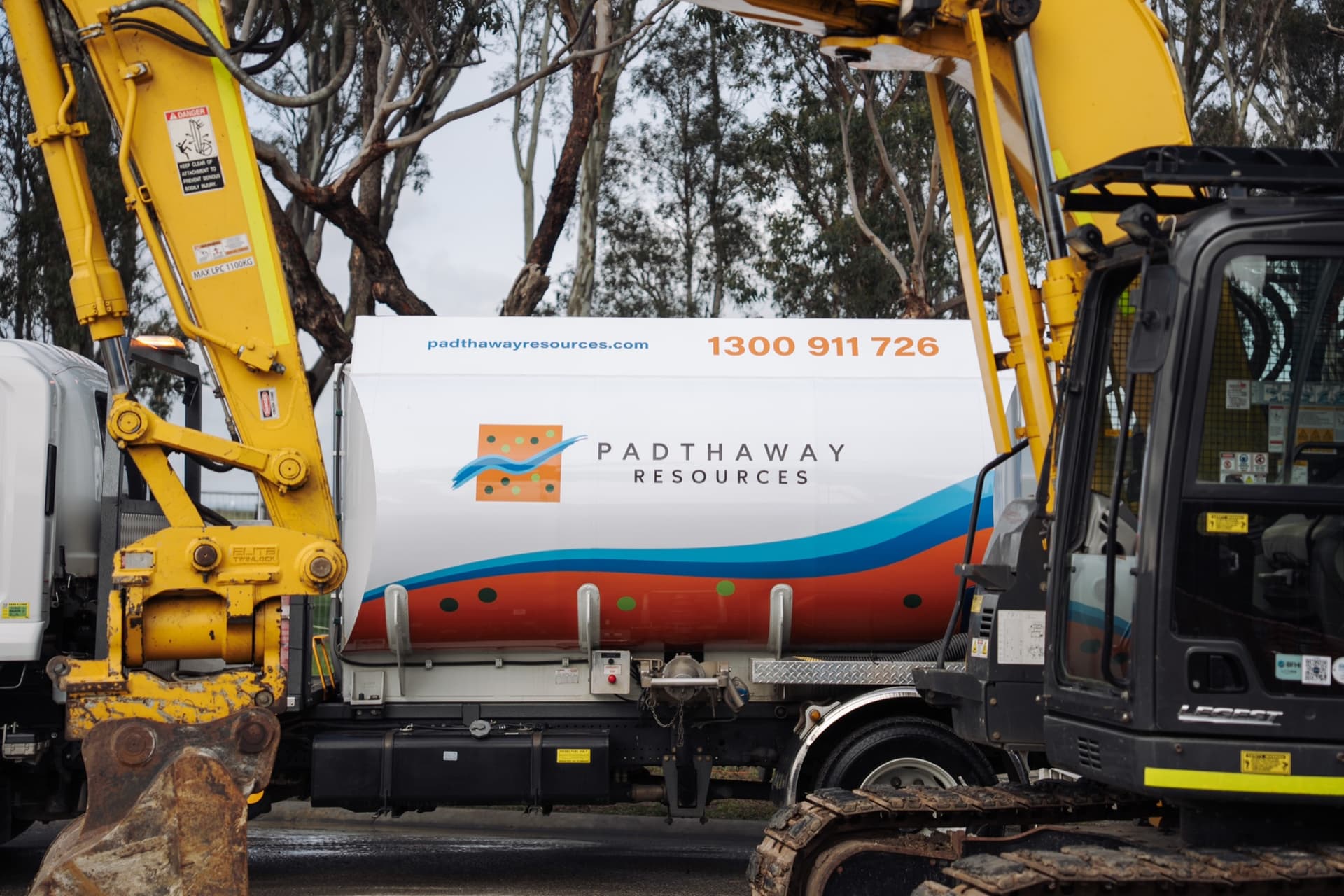 A Padthaway Resources tanker in the new livery, parked between two excavators on a civil site.