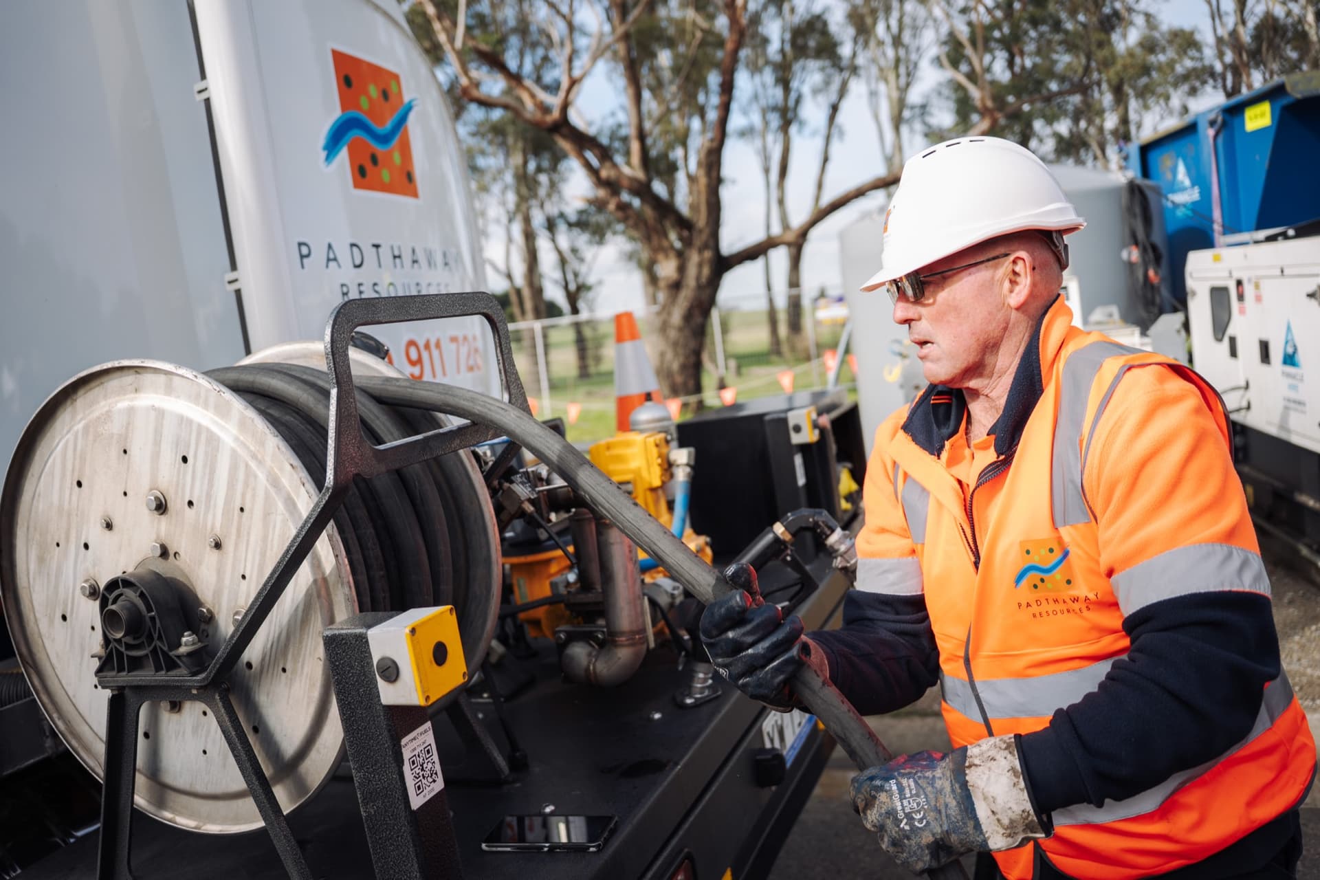An operator working the hose reel on the back of a branded Padthaway truck.