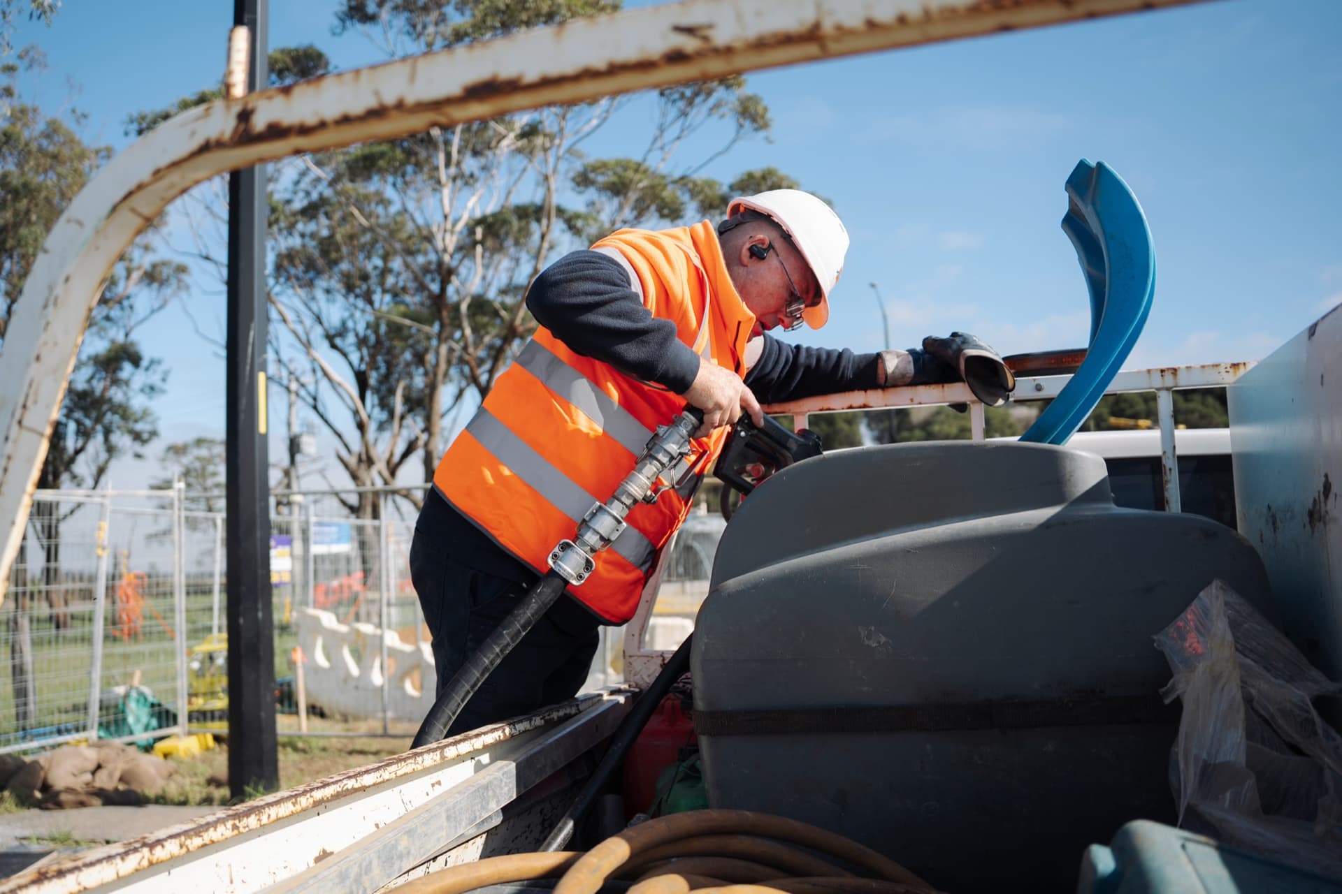 An operator refuelling a plant tank from the back of a truck.